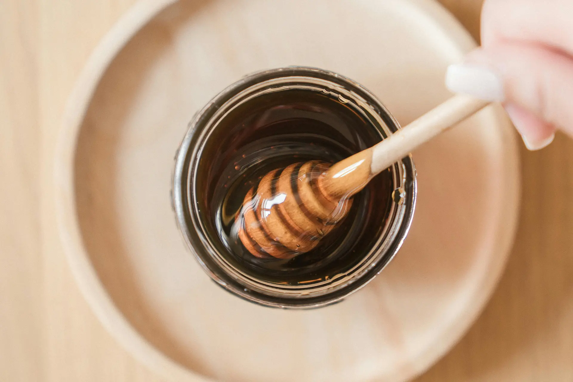 Honey being drizzled into a jar