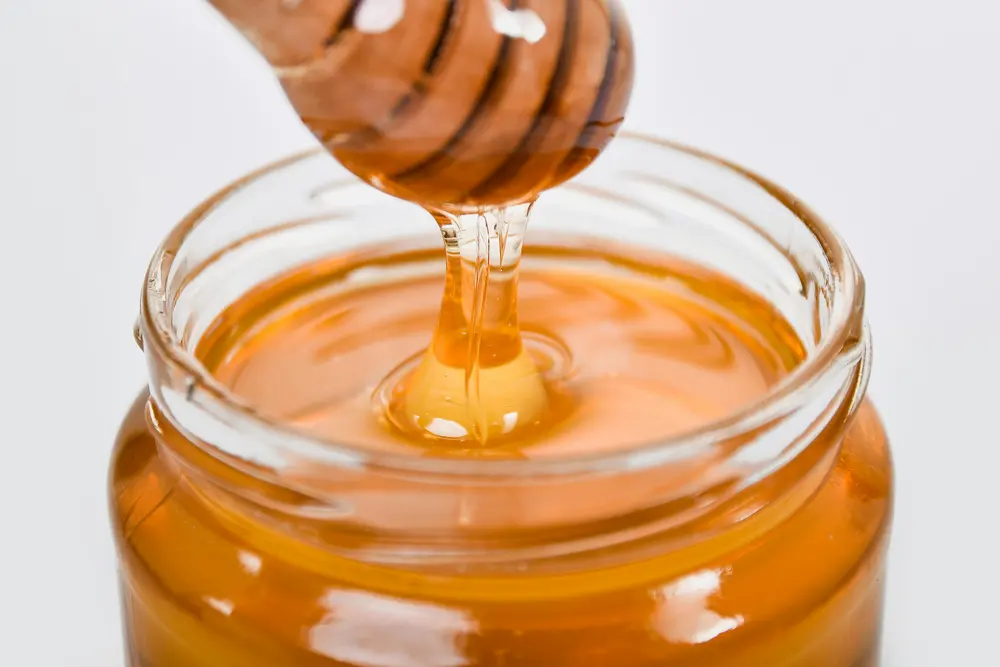 Honey being poured into a glass jar
